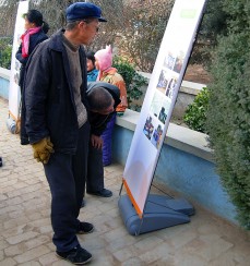 Villagers examining display board documenting the transformation of schools and volunteer activities at the schools.